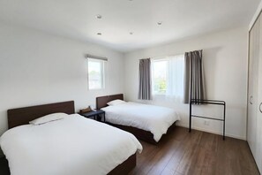 A hotel room with two beds, a nightstand, a desk, a chair, and a window with curtains. - star residence (Inzai)