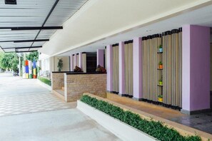 A covered outdoor area with a reception desk, vertical paneling, and a paved walkway. - Wangkaew Hotel, Phitsanulok (Phitsanulok)