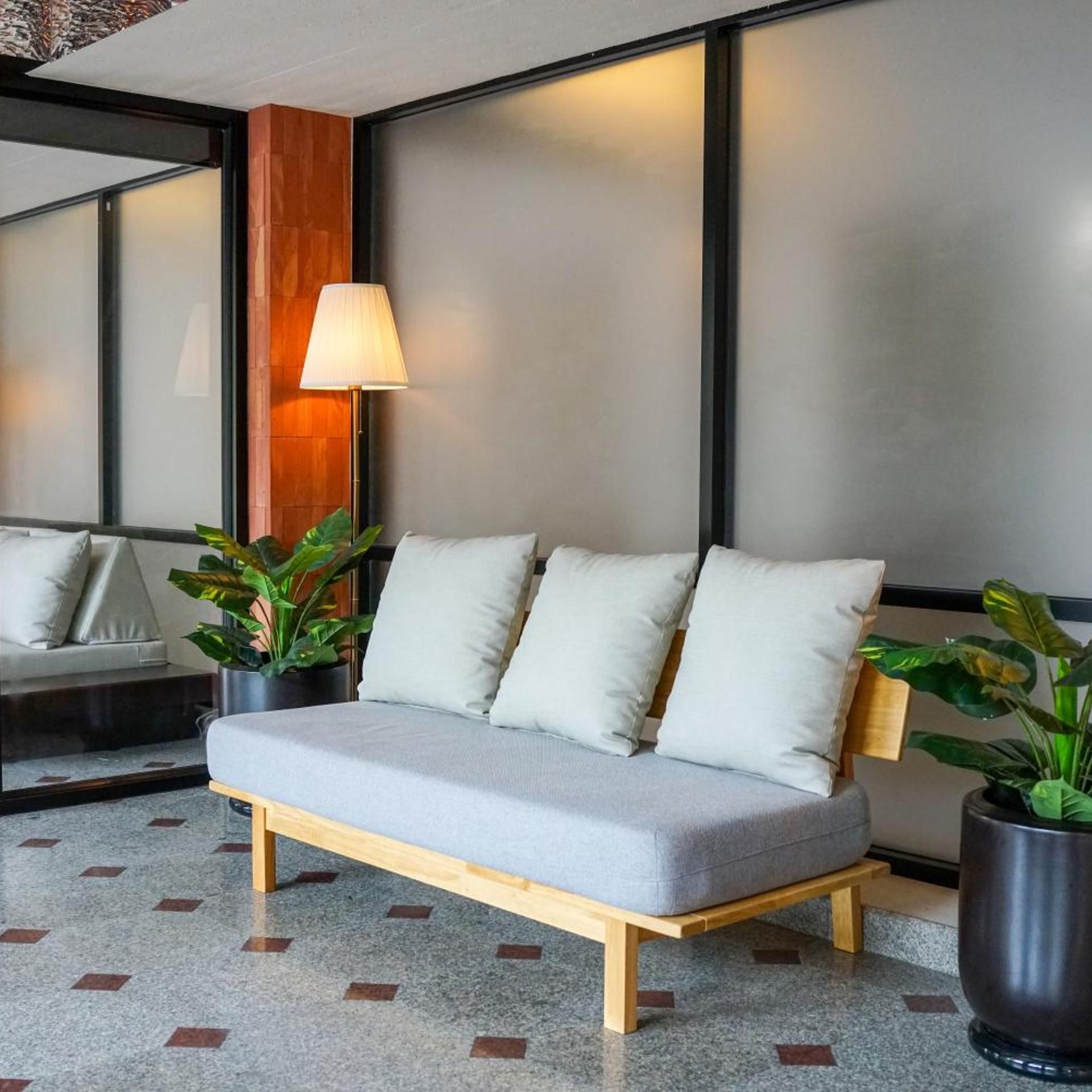Una habitación moderna con sofá gris, suelo de madera y ventanas amplias.