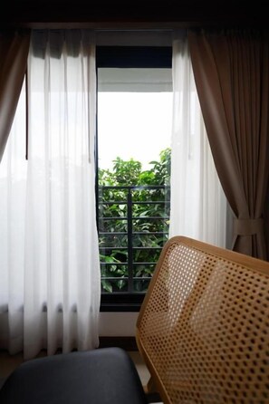 A room with a window, a chair, and a view of greenery outside. - Wangkaew Hotel, Phitsanulok (Phitsanulok)