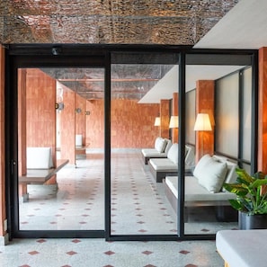 Een hotel lobby met een modern design, met een receptiebalie, zithoek en een glazen scheidingswand.