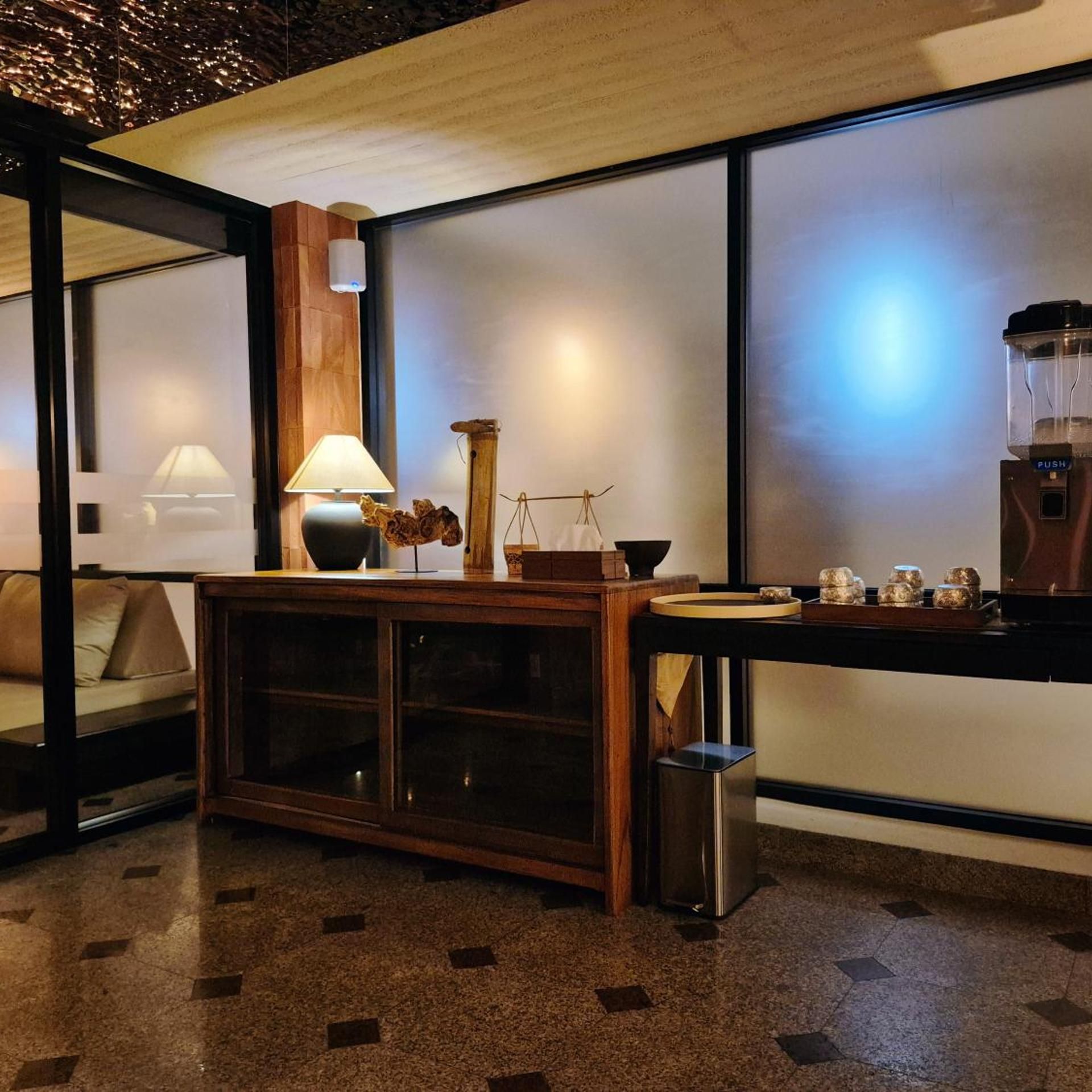A modern hotel room with a sofa, a coffee machine, a scale, and a small trash bin.