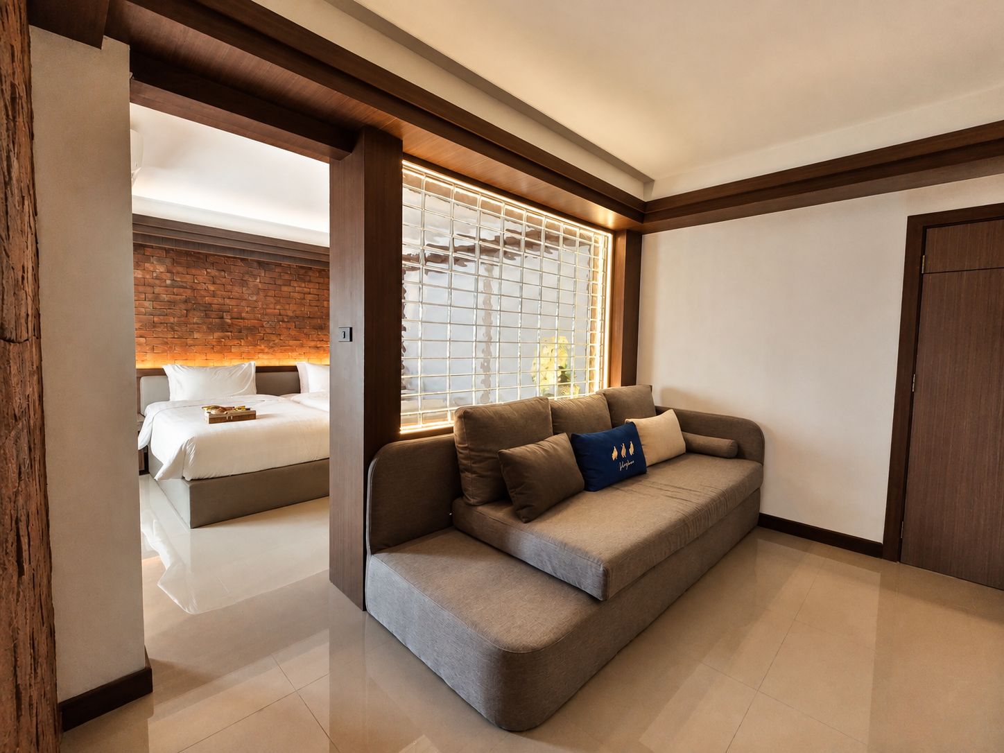 Habitación de hotel moderna con sofá, cama y un amplio ventanal con vistas.