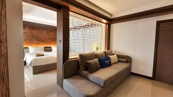 Habitación de hotel moderna con sofá, cama y un amplio ventanal con vistas.