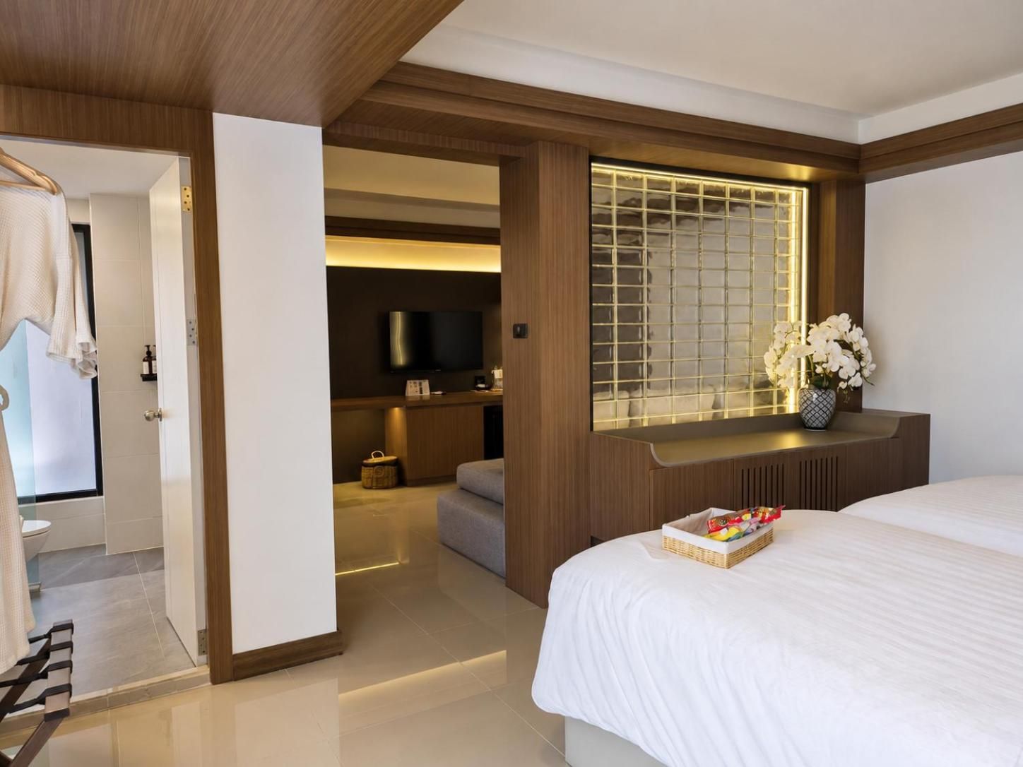 A hotel room with a bed, a TV, a window with a view, and a bathroom visible through an open door.
