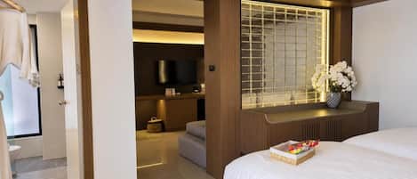 Una camera d'albergo con un letto, una televisione, una finestra vista bagno visibile attraverso una porta aperta.