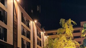 A multi-story hotel building with a central courtyard, featuring a well-lit entrance and surrounding greenery. - Wangkaew Hotel, Phitsanulok (Phitsanulok)