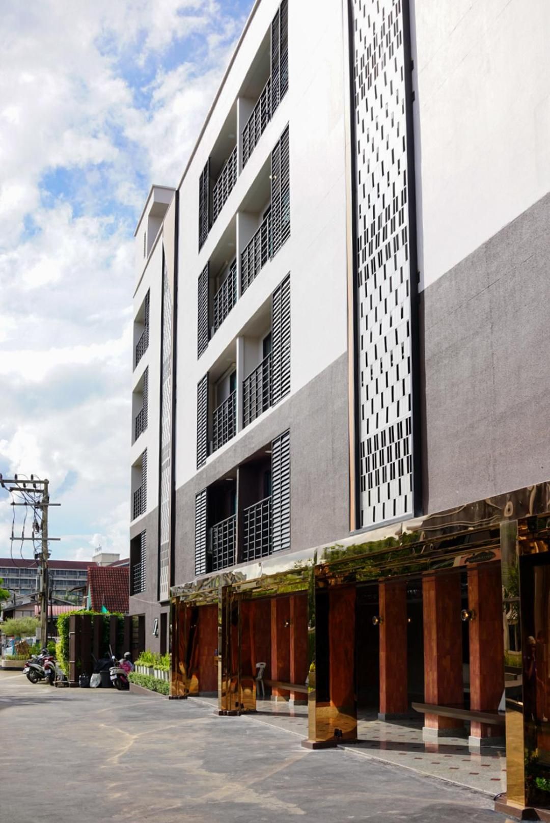 Een modern gebouw met meerdere verdiepingen, grote ramen en een overdekt terras met zitplaatsen.