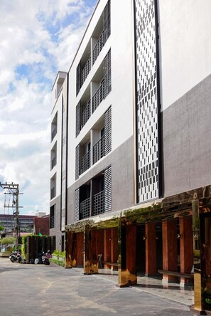 A modern building with multiple floors, large windows, and a covered outdoor area with seating. - Wangkaew Hotel, Phitsanulok (Phitsanulok)