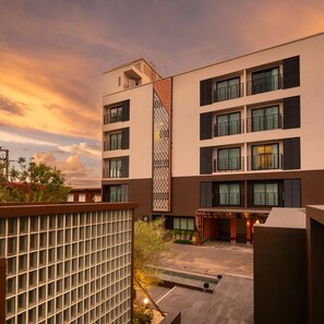 A modern multi-story building with balconies, a patterned facade, and a courtyard with a seating area. - Wangkaew Hotel, Phitsanulok (Phitsanulok)
