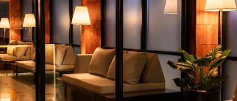 A hotel lobby with seating areas, lamps, and a large potted plant.