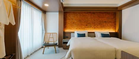A hotel room with a large bed, a small desk, a chair, and a brick accent wall.