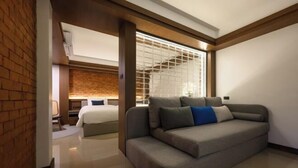 Ein modernes Hotelzimmer mit grauem Sofa, einem Bett und einer Ziegelwand.