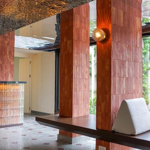 A modern interior with wooden pillars, a bench, and a wall-mounted light fixture. - Wangkaew Hotel, Phitsanulok (Phitsanulok)