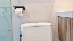 A modern bathroom with a toilet, a paper towel dispenser, and a wooden vanity. - Wangkaew Hotel, Phitsanulok (Phitsanulok)