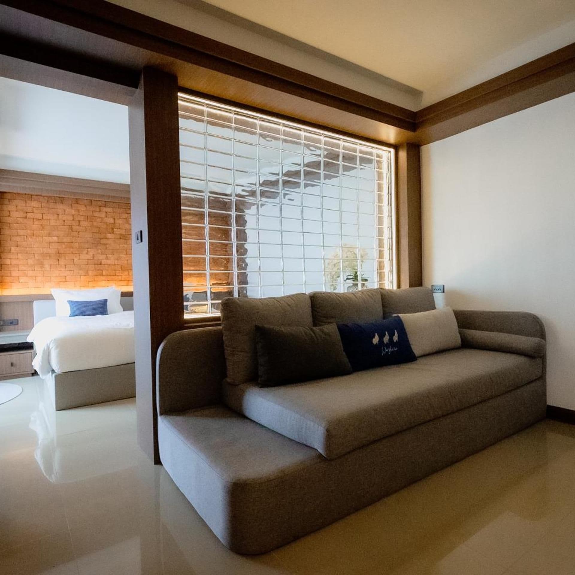 Een moderne hotelkamer met een bank, een bed en een raam met zonwering.