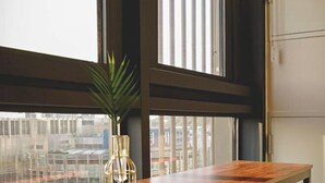 A modern kitchen with a wooden countertop, a potted plant, and a window with blinds. - SUNNY HOUSE (Seoul)