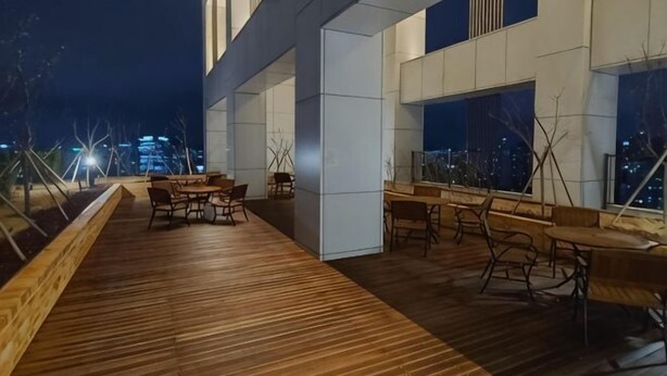 A modern building with a wooden deck and outdoor seating area. - SUNNY HOUSE (Seoul)