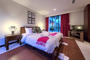 A hotel room with a large bed, a TV, a nightstand, and a window with curtains. - Baan Feung Fah (Koh Samui)
