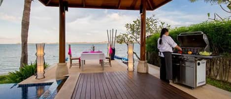 An outdoor deck with a grill, a pool, and a table with chairs.
