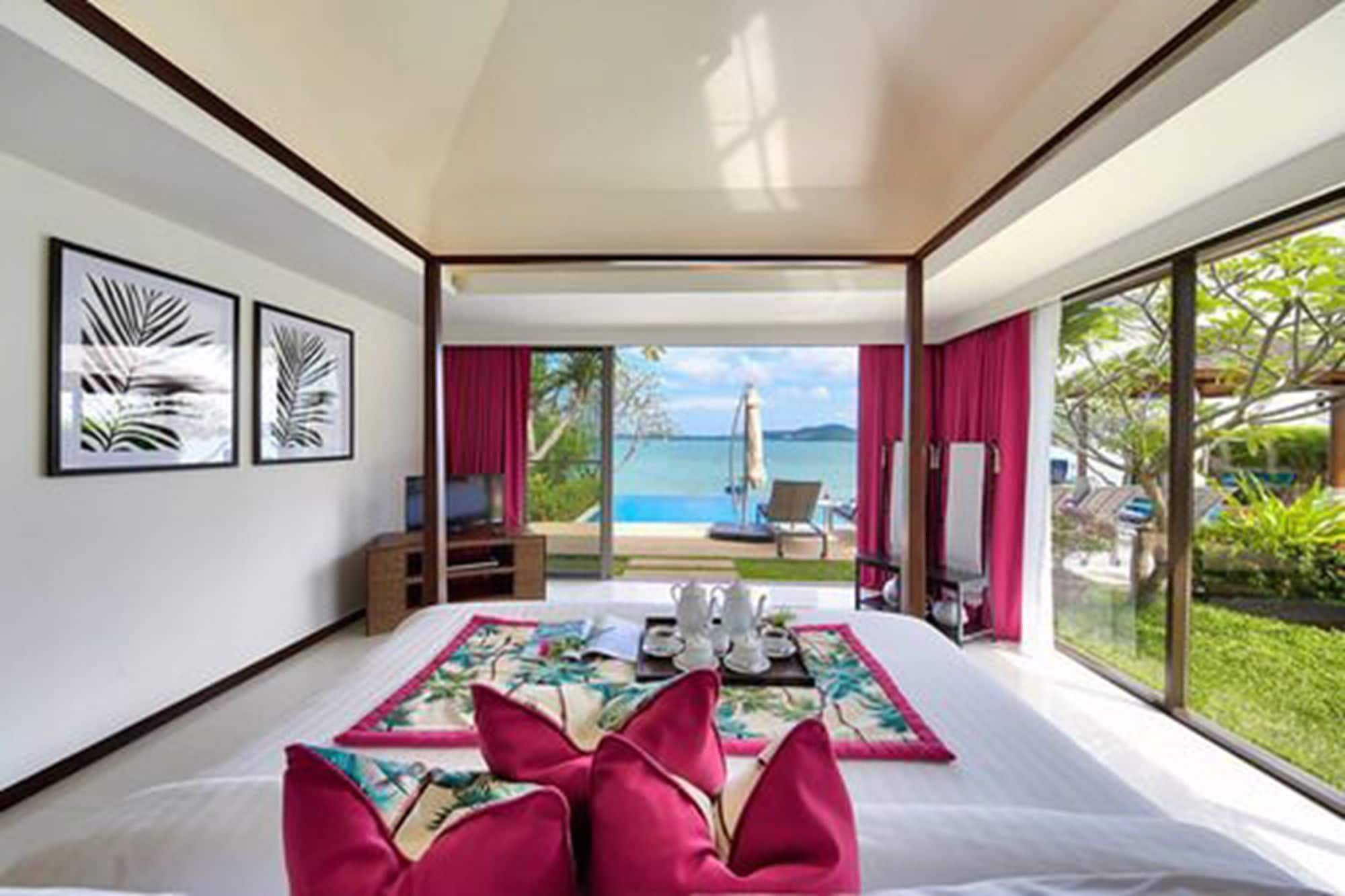 Une chambre d’hôtel avec un grand lit, une vue sur la mer et un balcon équipé d’une chaise et d’un parasol.