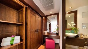 A bathroom with wooden cabinetry, a pink stool, a sink with a mirror, and a potted orchid. - Baan Feung Fah (Koh Samui)