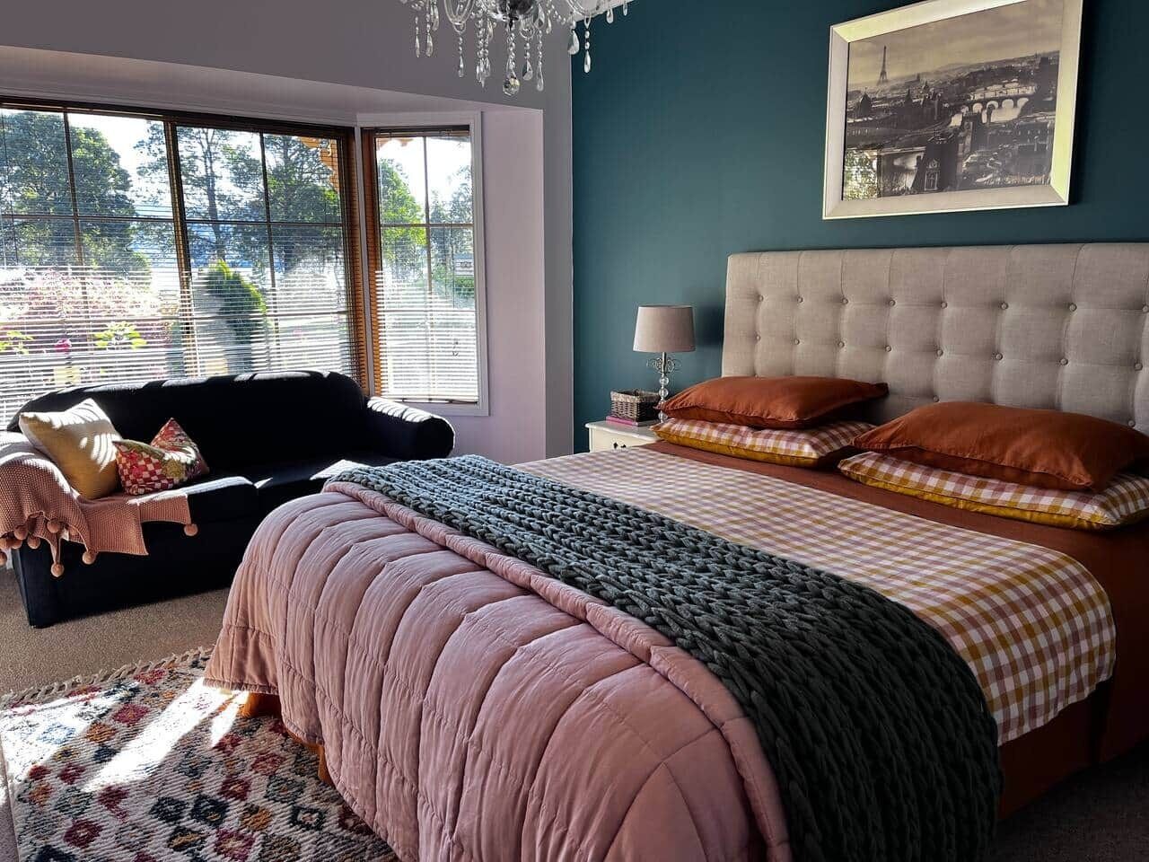 Una camera da letto con un letto grande, un divano nero e una finestra con persiane.