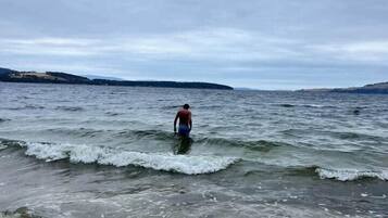 A beach scene with a person walking in the water.