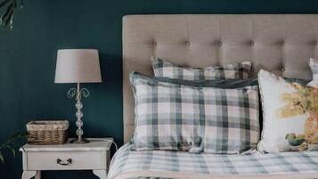 A bedroom with a tufted headboard, a checkered bedspread, and a framed picture of a cityscape.