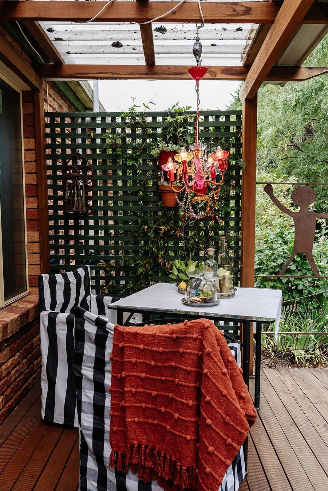 Un patio couvert avec une table, des chaises et un lustre décoratif.