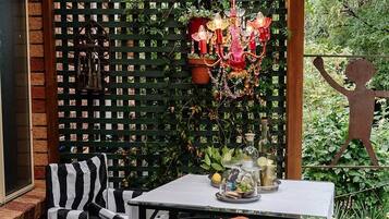Un patio couvert avec une table, des chaises et un lustre décoratif.