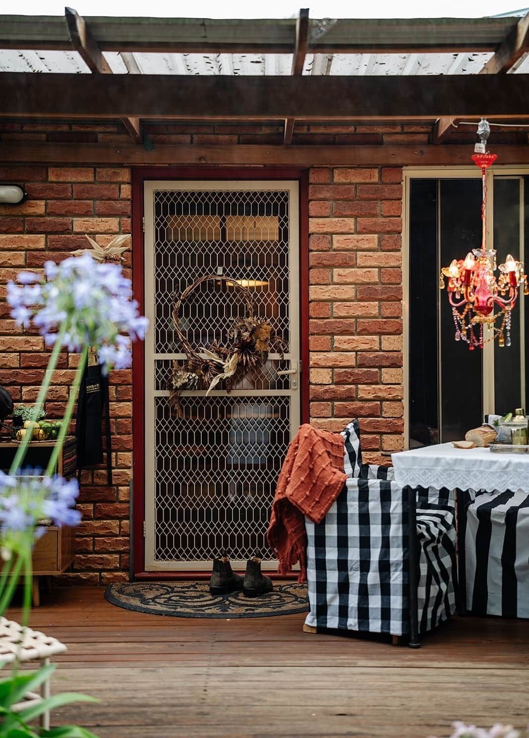 A brick exterior with a metal gate, a table with a white tablecloth, and a chandelier.