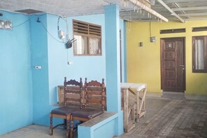 A room with a wooden bench, a window with a shutter, and a door.