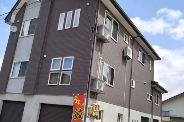Un immeuble à plusieurs étages, doté d’une façade plate, de nombreuses fenêtres et d’un appareil de climatisation visible.