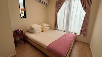 A bedroom with a bed, a nightstand, and a window with curtains.