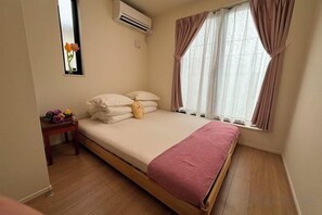 Un dormitorio con cama, mesita de noche y ventana con cortinas.