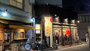 Un restaurant à la façade en briques, avec une entrée en verre et des vélos garés à l’extérieur.