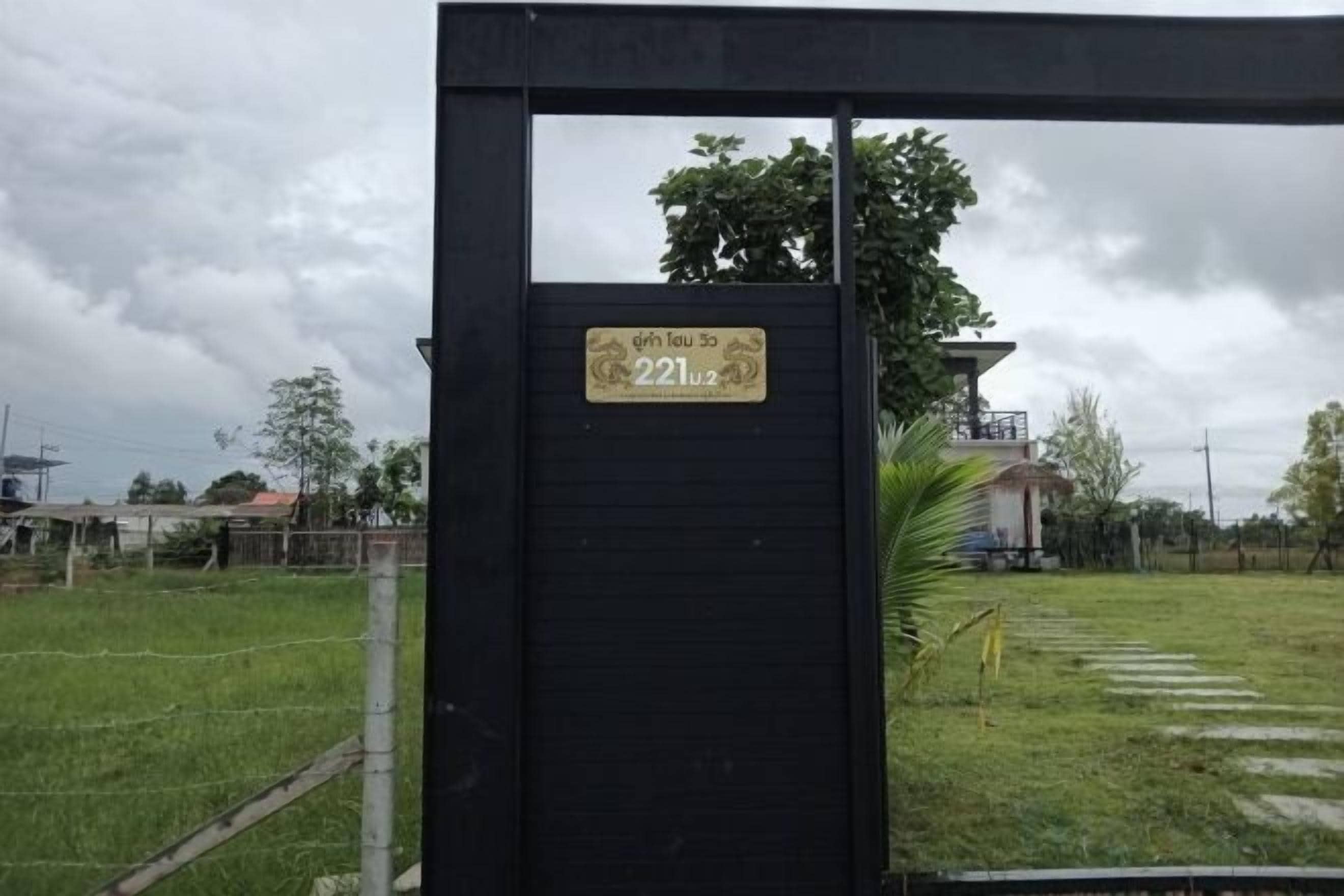 A black metal gate with a sign indicating a property number.