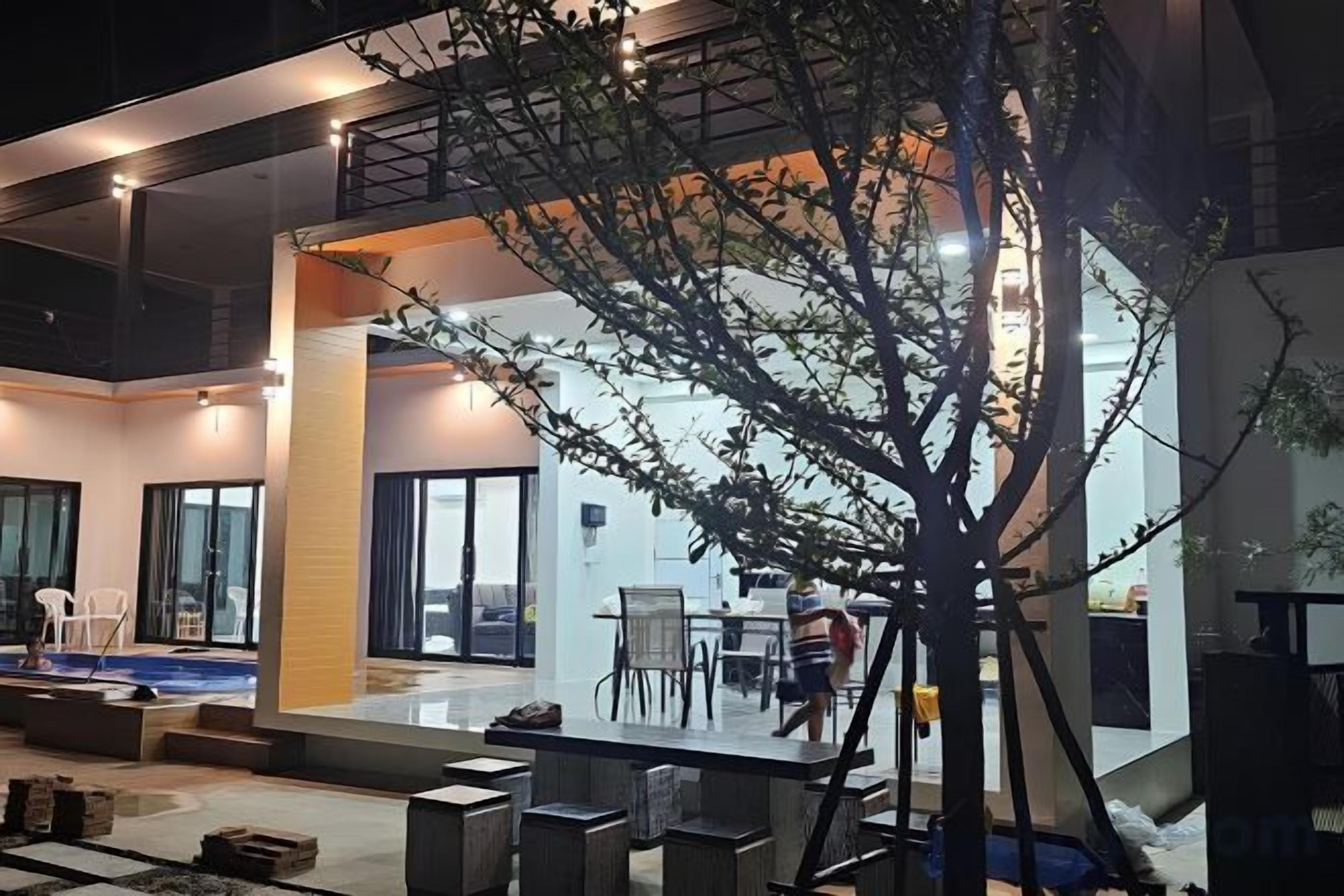 A modern indoor space with a dining area, a staircase, and a tree sculpture.