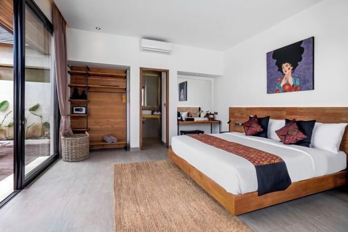 Une chambre moderne avec un grand lit, une tête de lit en bois, un bureau et une grande fenêtre.