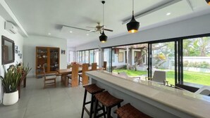 Une cuisine moderne dotée d’un coin bar, de grandes fenêtres et d’un ventilateur de plafond.