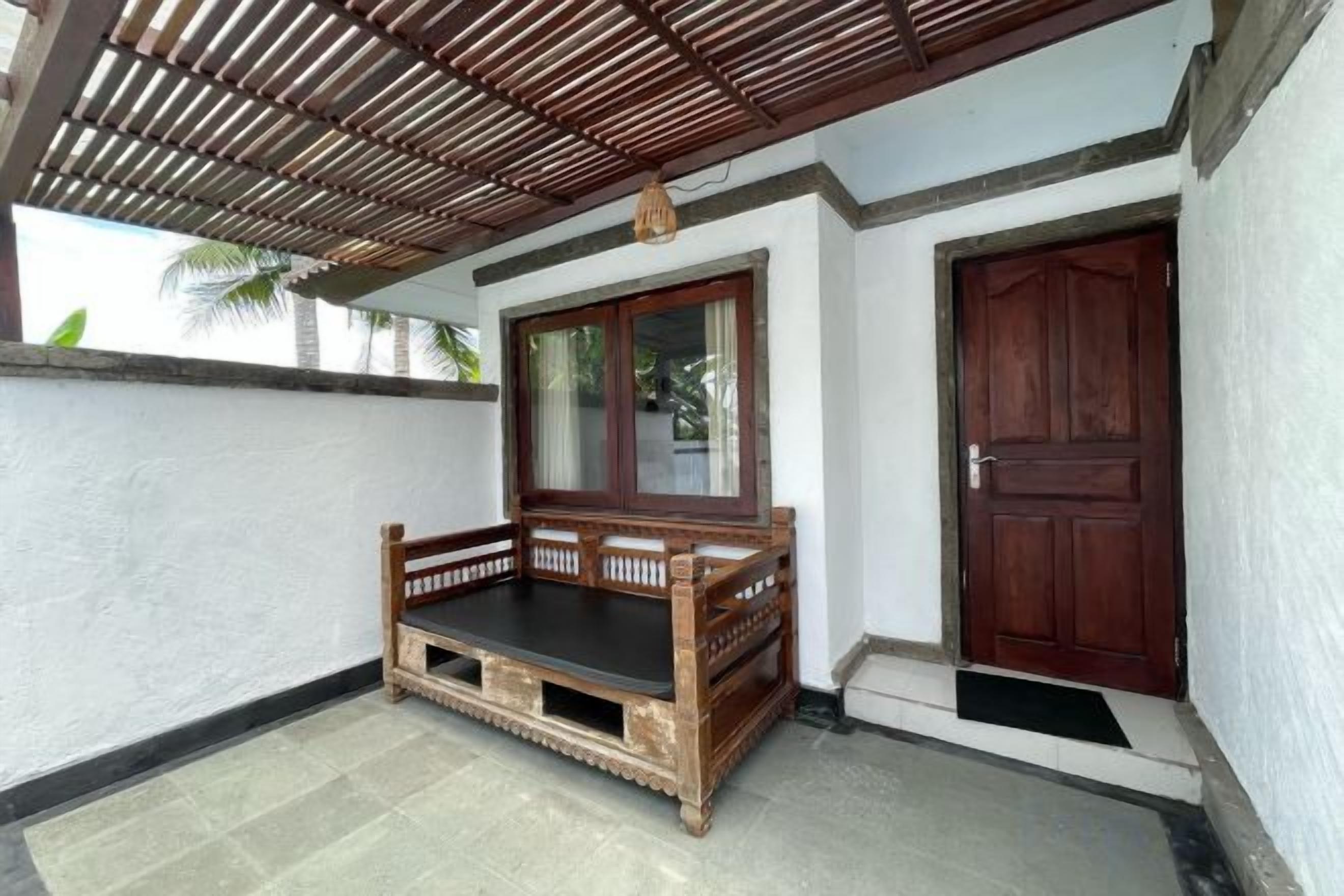 Un portico riparato con una panchina di legno, una porta e una finestra.