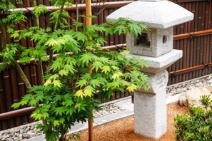 A stone lantern with a small tree in front of a bamboo fence. - TAKAYAMA KAEDENOYADO (Takayama)