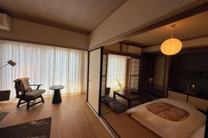 A traditional Japanese-style room with tatami flooring, a low table, a sofa, and a bed with a futon. - TAKAYAMA KAEDENOYADO (Takayama)