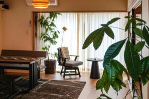 A room with a dining table, chairs, a sofa, a potted plant, and a hanging plant. - TAKAYAMA KAEDENOYADO (Takayama)