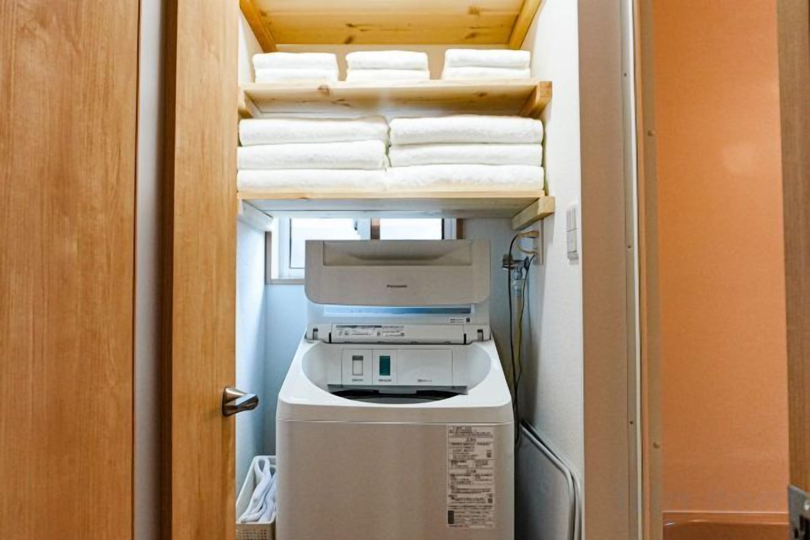 Een compacte kamer met een houten plafond, een bed en een klein raam.