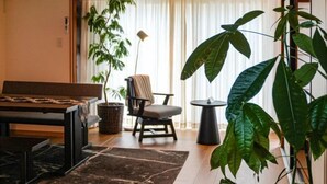 A room with a wooden bench, a chair, a small table, and a potted plant. - TAKAYAMA KAEDENOYADO (Takayama)
