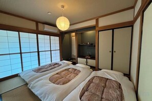 A traditional Japanese-style room with tatami flooring, a shoji screen, and a futon bed. - TAKAYAMA KAEDENOYADO (Takayama)