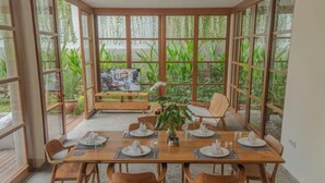 Un coin repas avec une grande table en bois, dressée pour six personnes, entourée de chaises en bois.