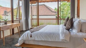 Une chambre à coucher avec un lit, un bureau en bois et une vue sur l’extérieur.